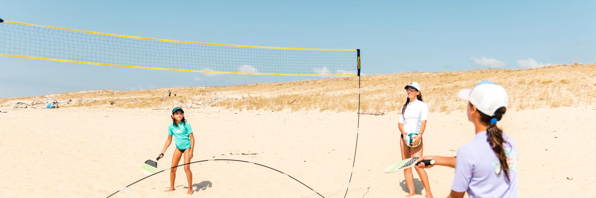 Nastolatki grające w badmintona na plaży w towarzystwie mamy dba o formę dzieci