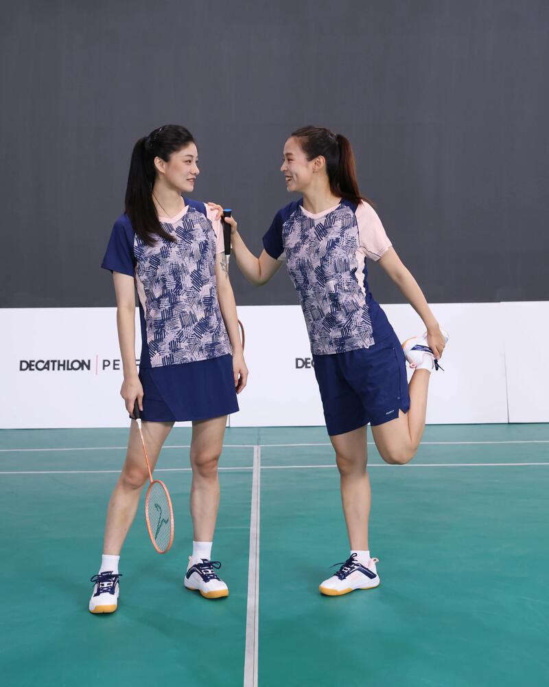 Zwei Frauen dehnen sich auf einem Badmintonplatz.