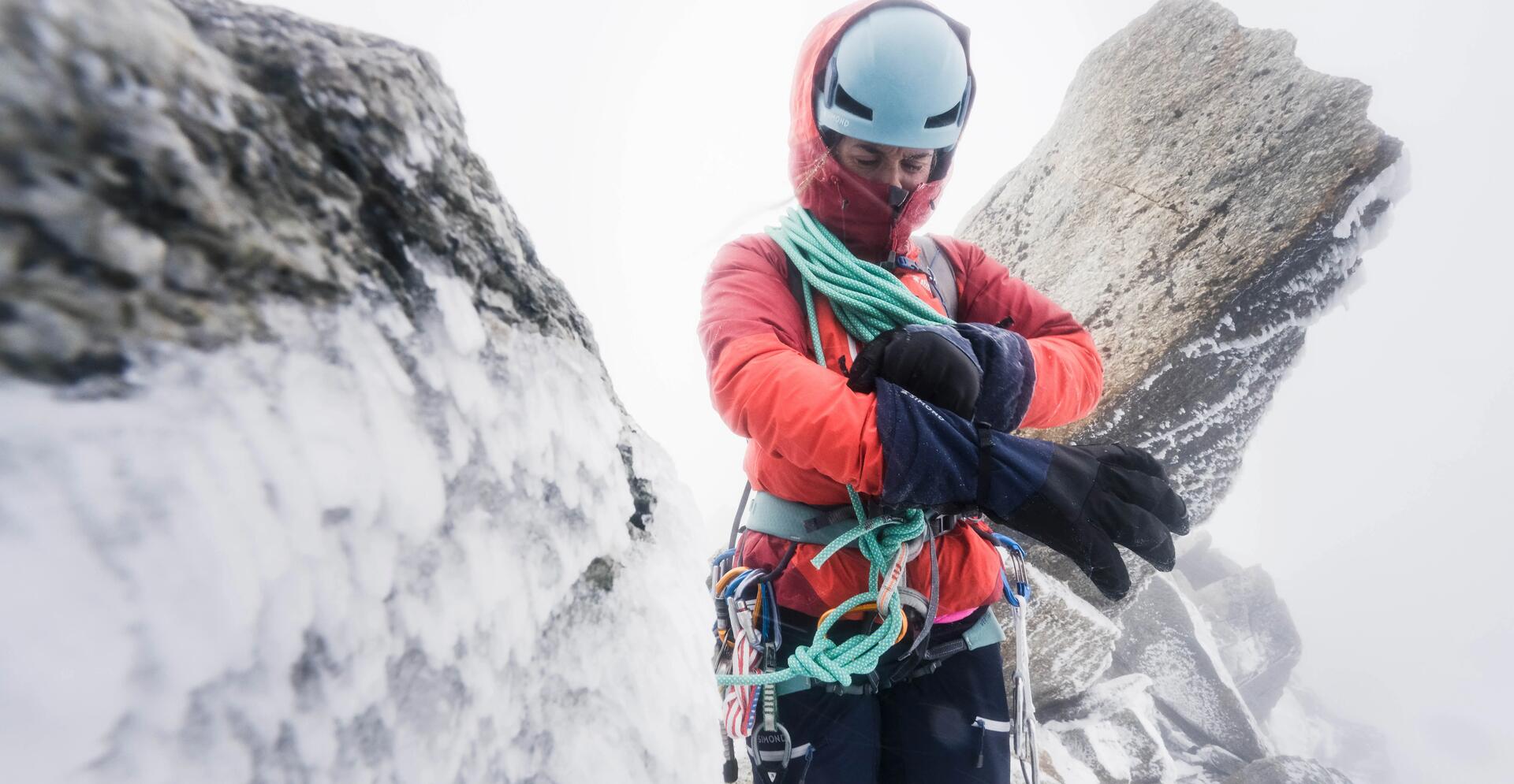 kobieta w stroju alpinistycznym z uprzężą nakładająca rękawiczki