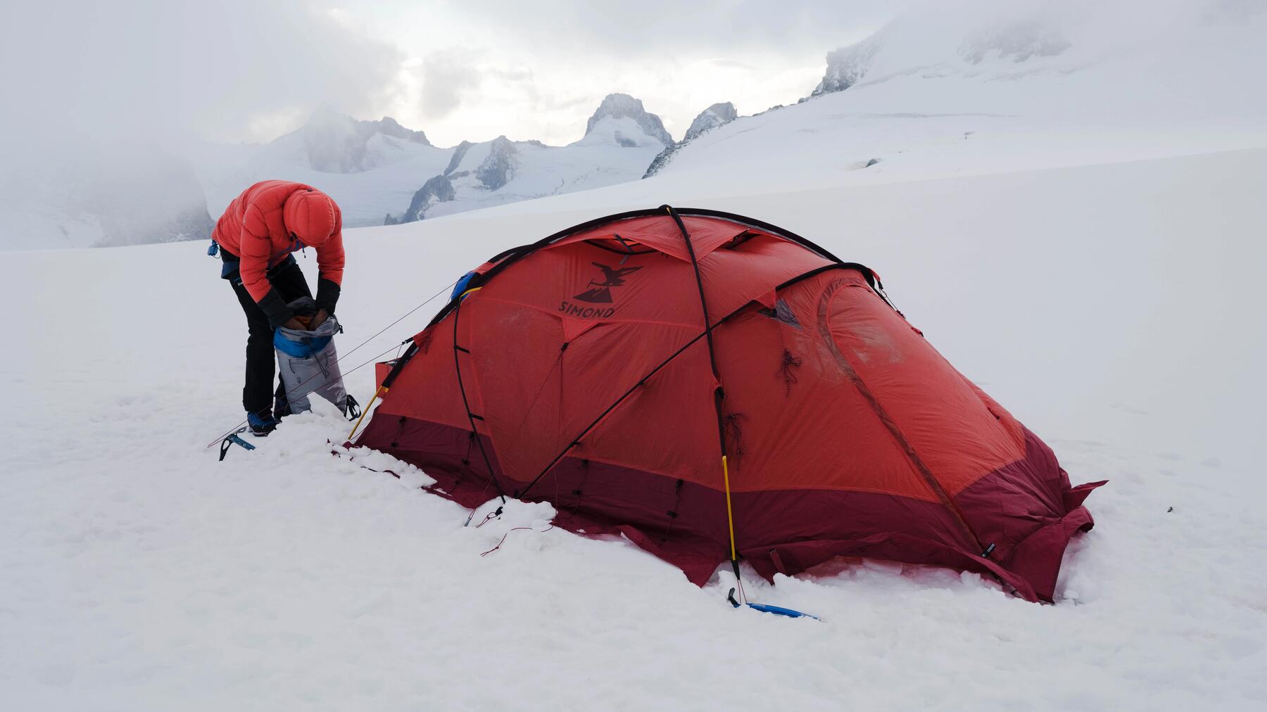 Mężczyzna stojący przed rozłożonym namiotem alpinistycznym w górach chcący zdobyc Mount Everest