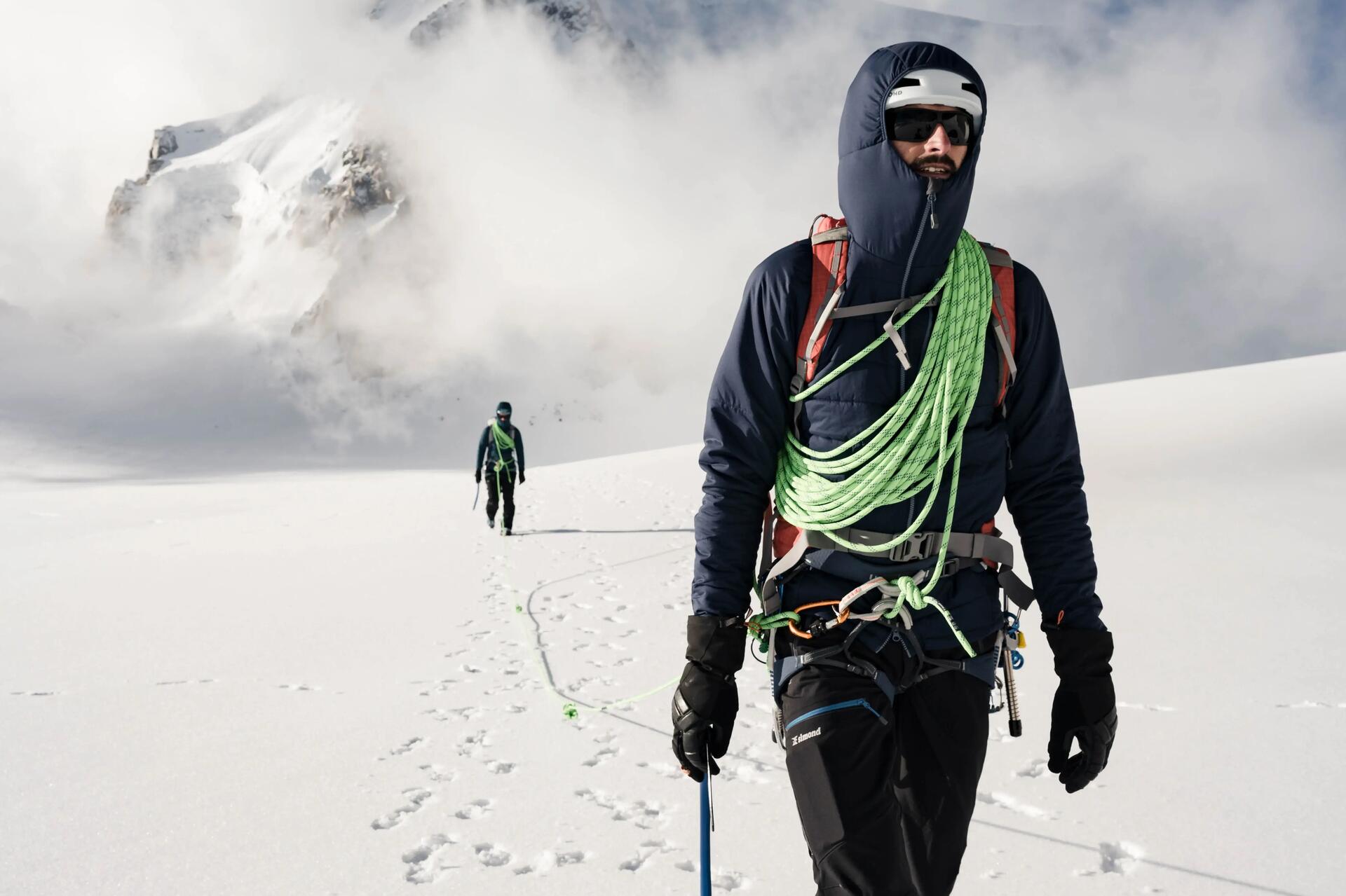 Osoby w odzieży alpinistycznej wędrujące po górach zimą
