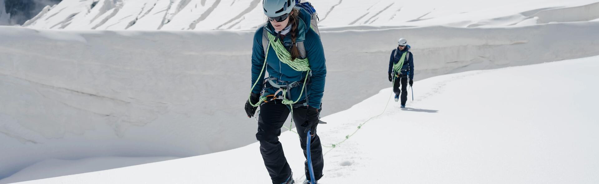 kobieta i mężczyzna w zimowej odzieży trekkingowej wędrujący po śniegu w górach