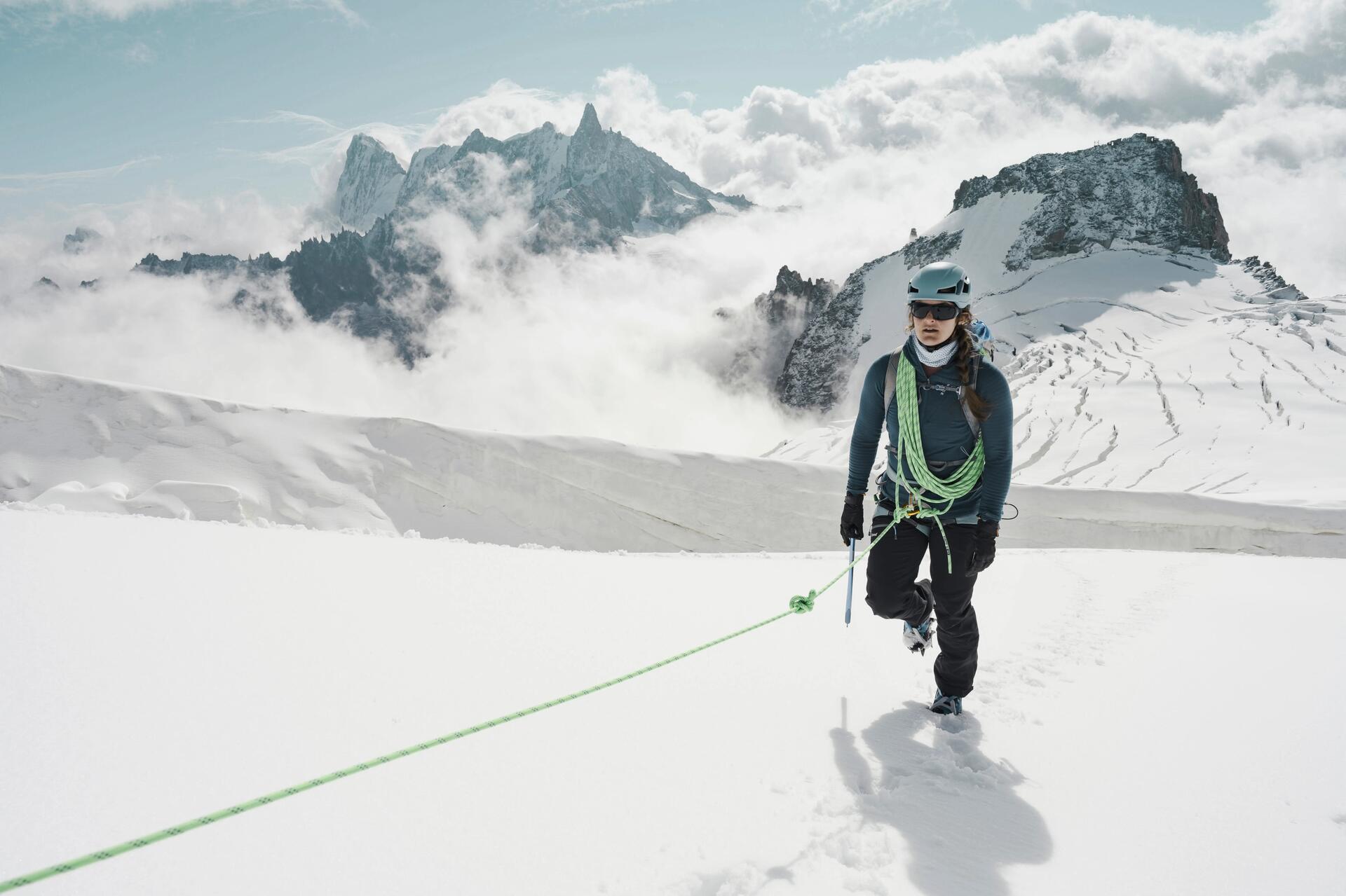Kobieta w kasku z założoną uprzężą uprawiająca trekking pod lodowiec