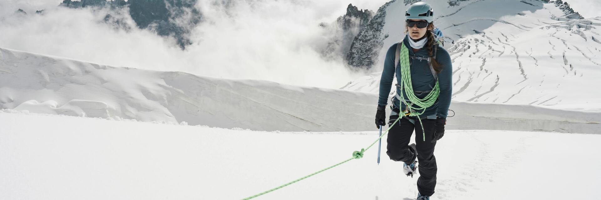 Kobieta w kasku z założoną uprzężą uprawiająca trekking pod lodowiec