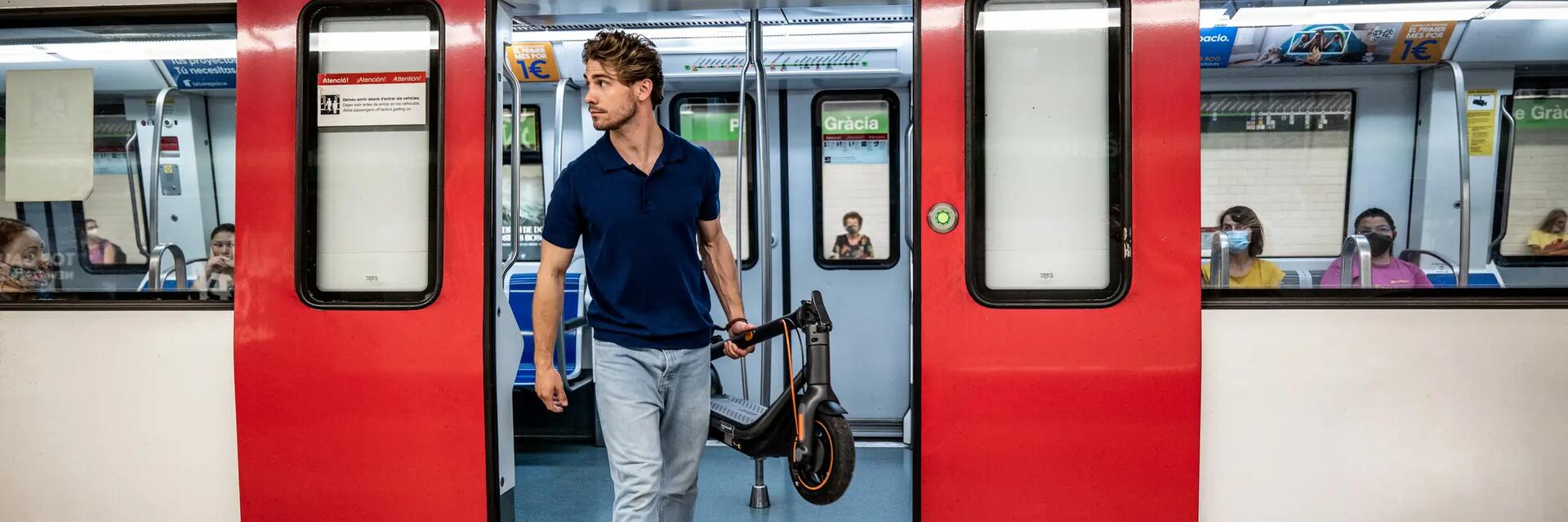 Mężczyzna wychodzący z metra ze złożoną hulajnogą elektryczną