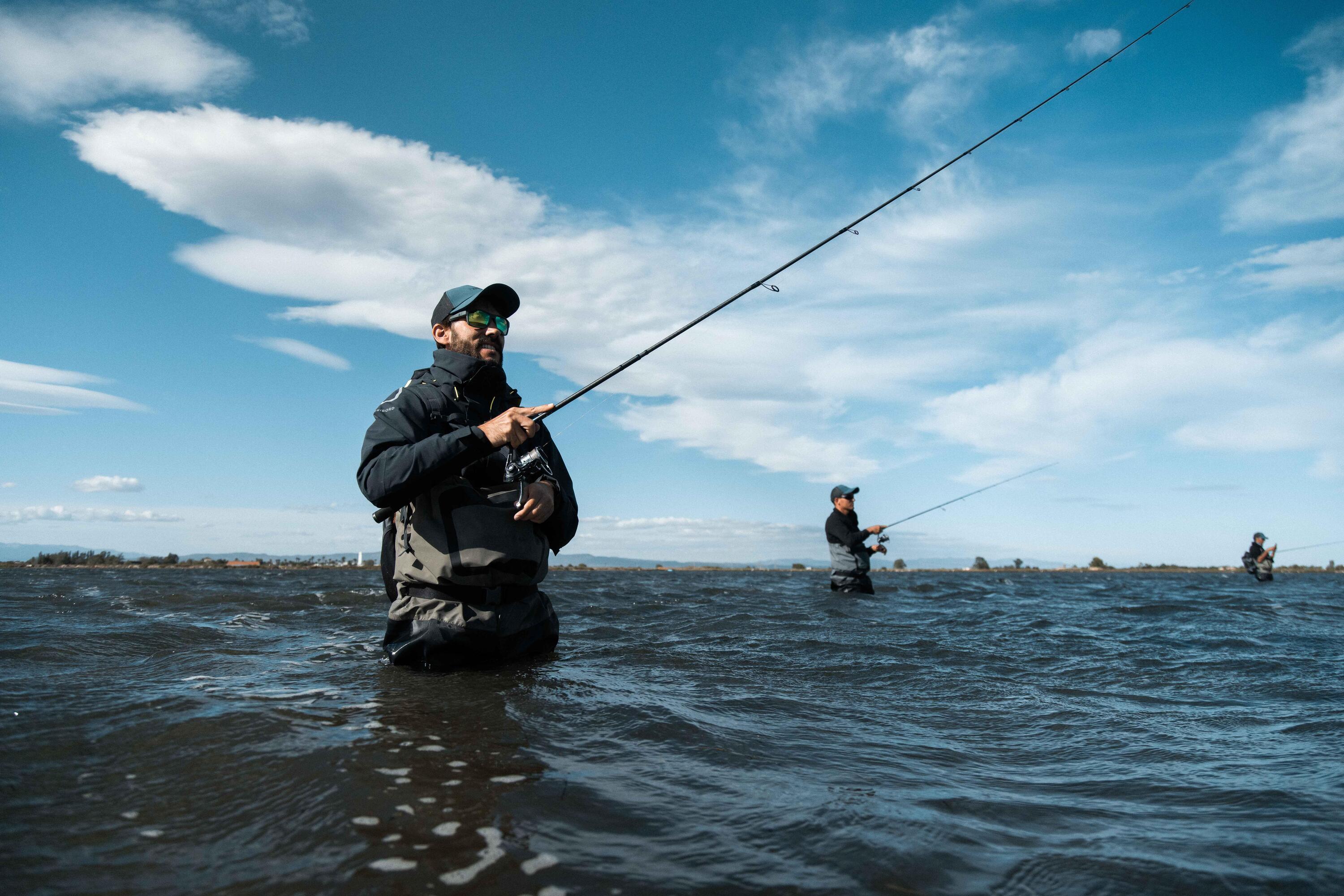 Mehrere Angler stehen im Wasser am Meer und werfen ihre pinnruten aus