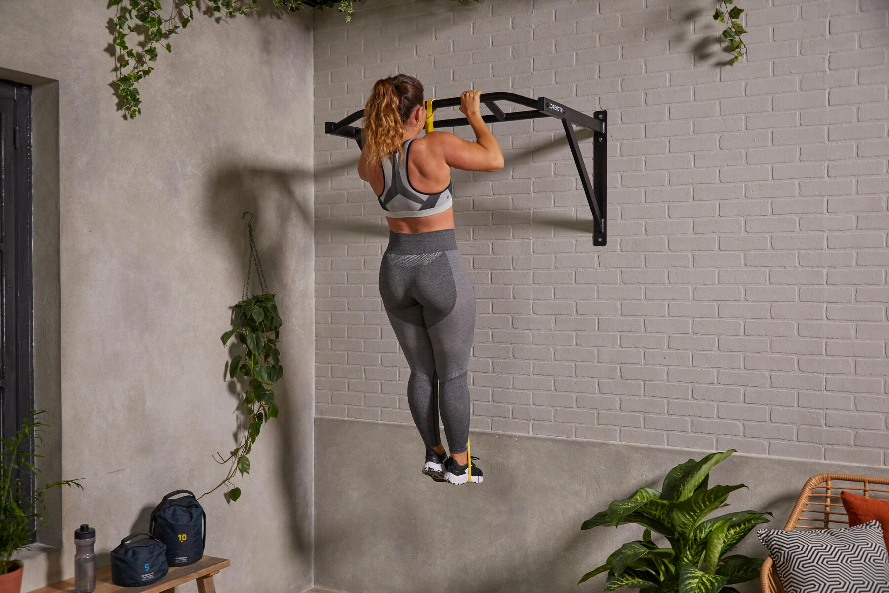 Kobieta podciągajaca się na drążku w stroju fitness
