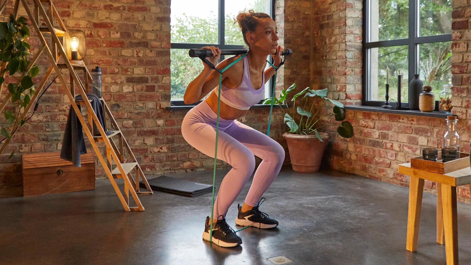 Dziewczyna w stroju fitness ćwicząca na drążku z gumami oporowymi
