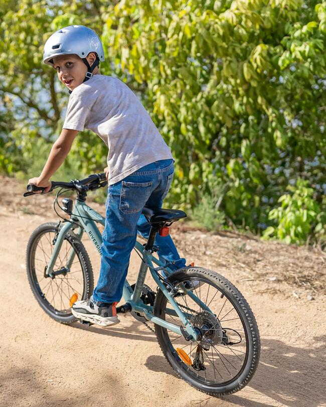 Kind fährt auf grünem Fahrrad einen Weg entlang