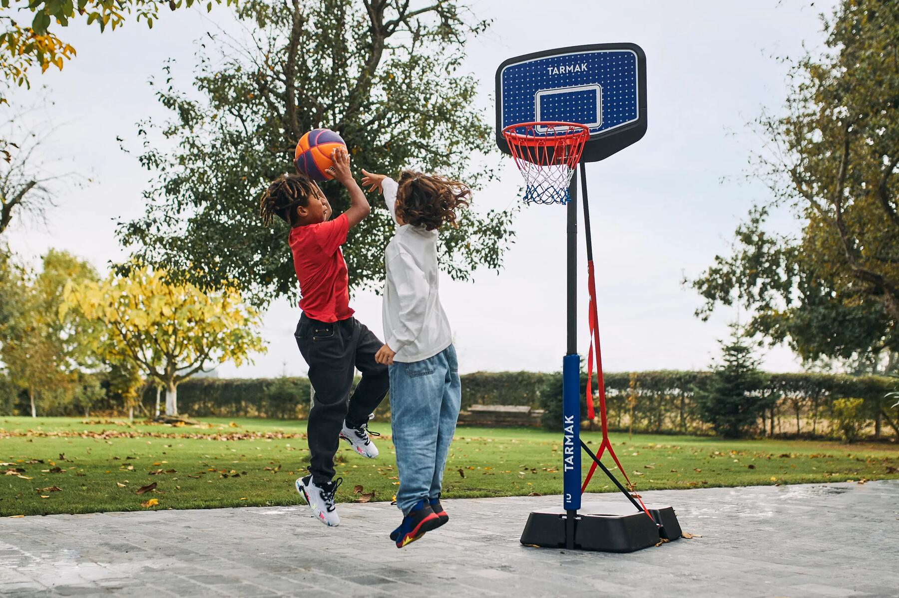 Zwei Kinder spielen Basketball im Garten im Herbst.