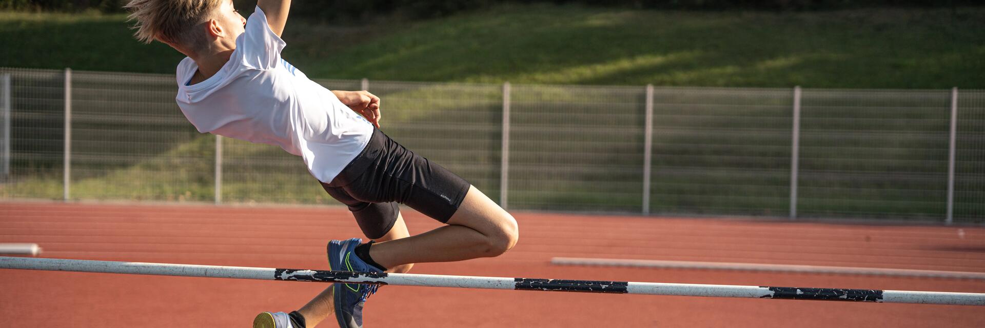 Nastolatek w odzieży sportowej skaczący wzwyż
