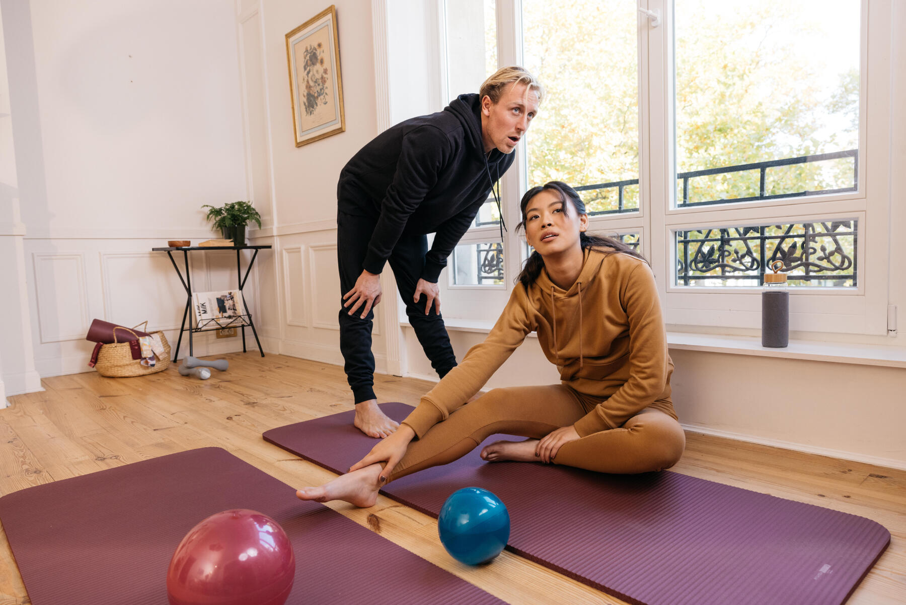 Mann und Frau sind erschöpft und sitzen auf Yogamatten um ihren oberen Rücken zu trainieren