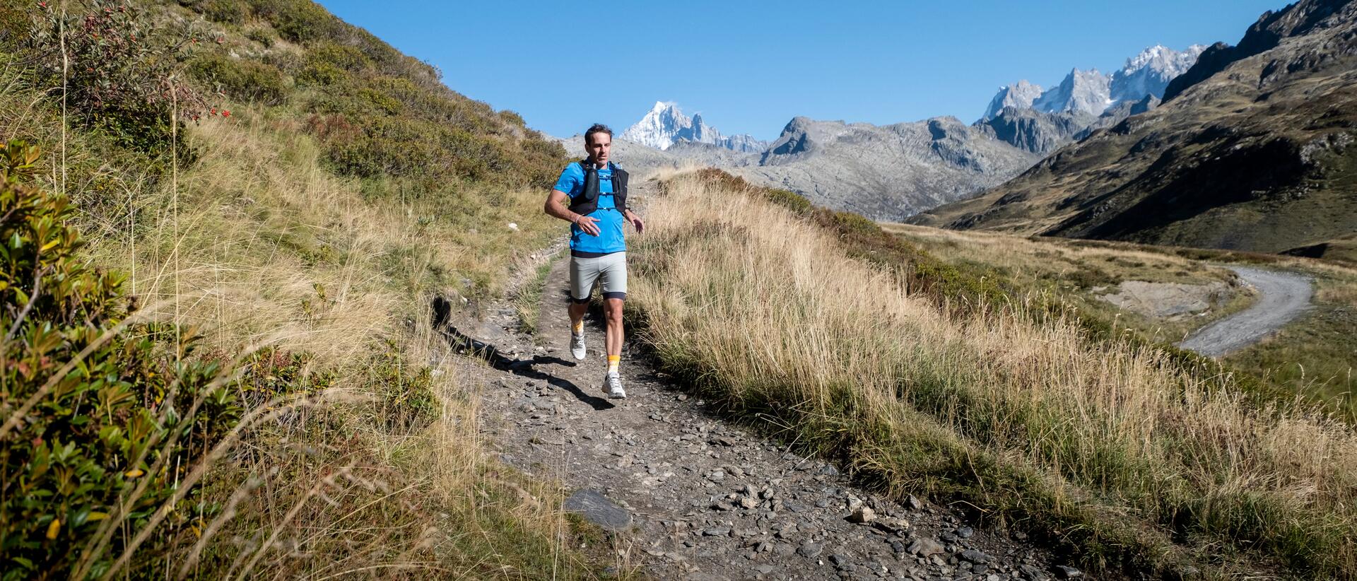 A man trail running in some hills and mountains