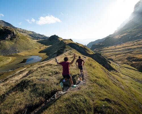 man and woman running on a scenic green mountain trail