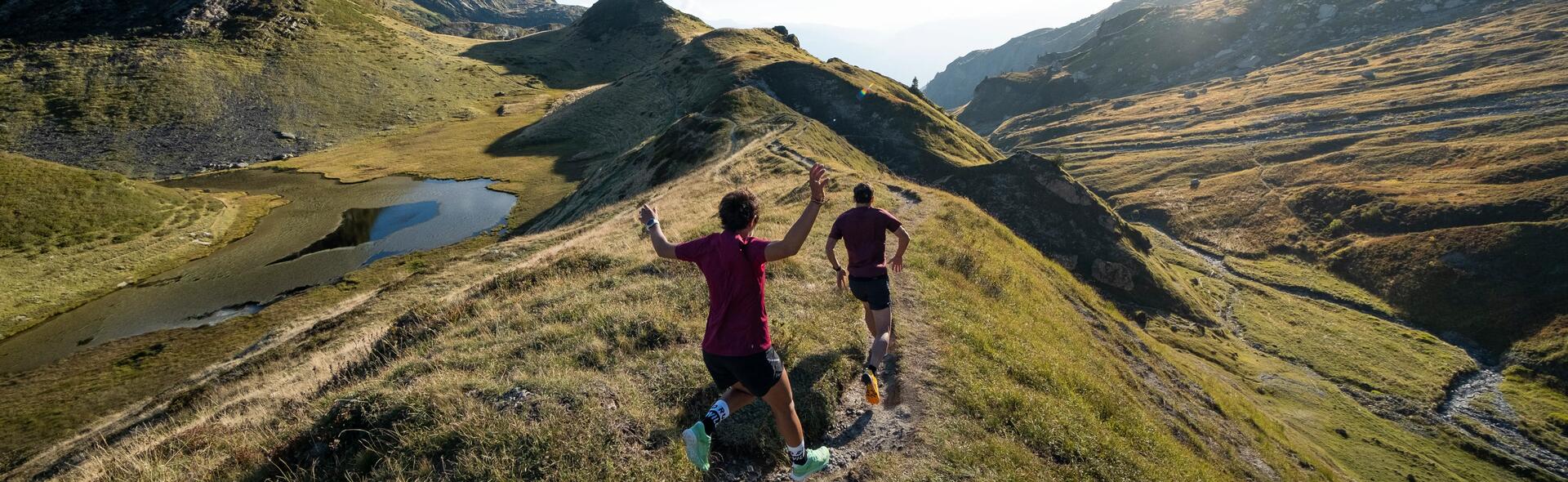 man and woman running on a scenic green mountain trail