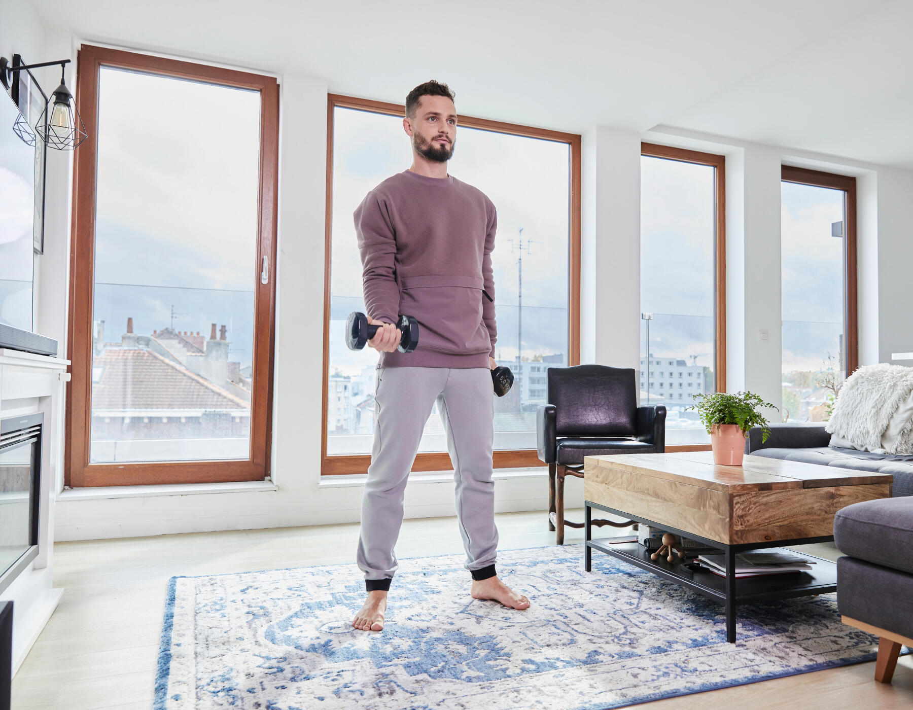 homem a praticar exercício em casa com halteres de 5kg de pilates