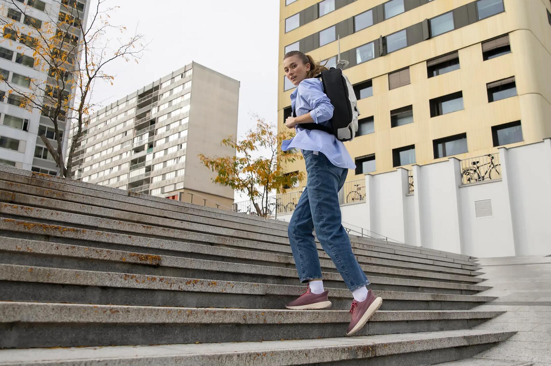 femme qui monte un escalier urbain et qui regarde de profil le photographe qui est légèrement en contrebas sur sa gauche