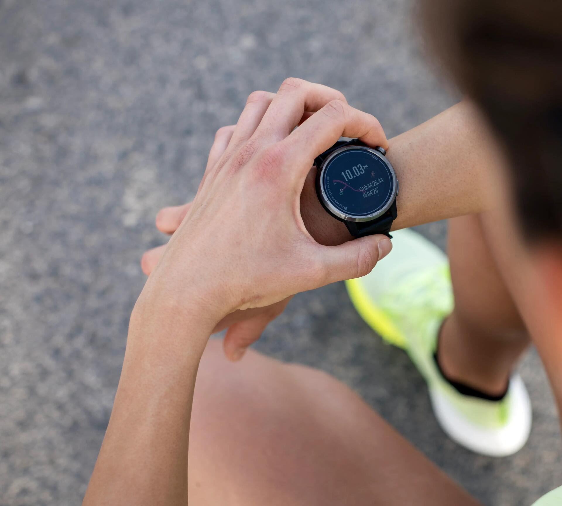 person holding smartphone and wearing a GPS watch