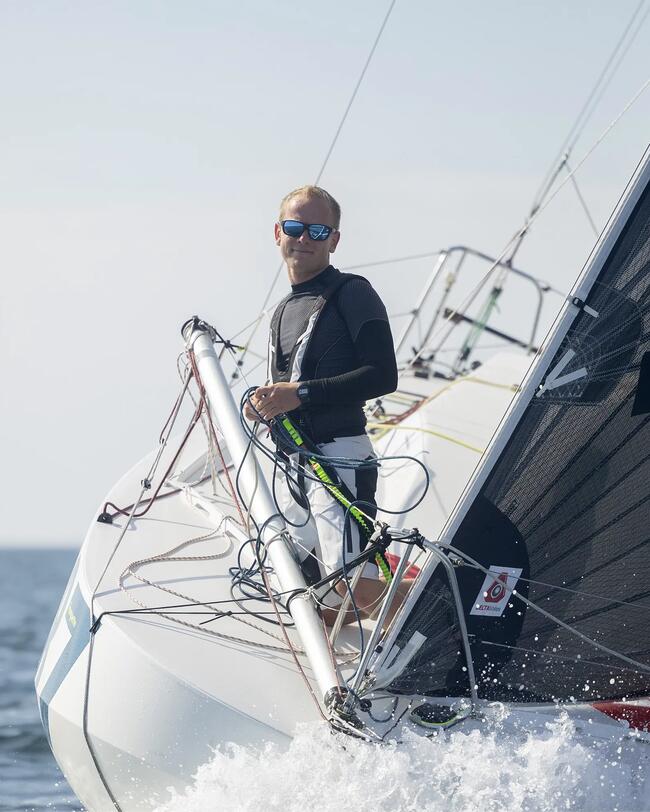 marinheiro com um arnês na proa de um barco