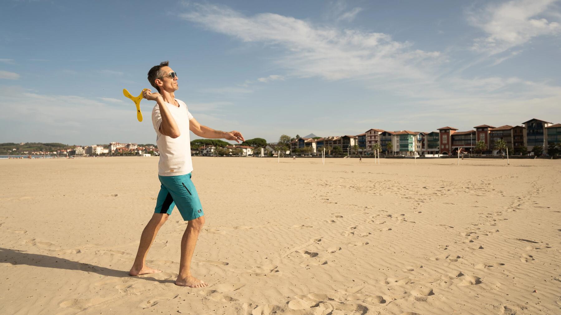 Ein Mann am Meer in perfekter sportlicher Haltung beim Wurf eines Bumerangs