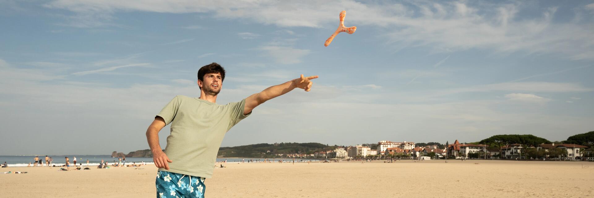 Ein Mann wirft am Strand einen Bumerang