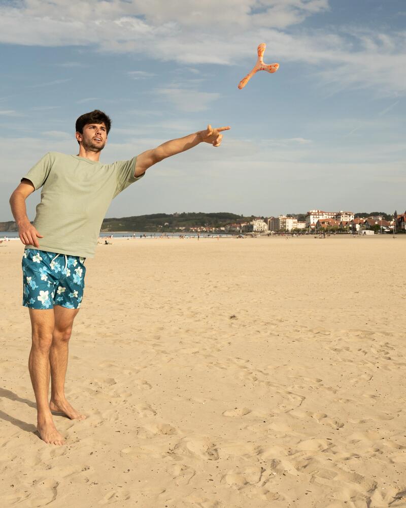 Ein Mann wirft am Strand einen Bumerang