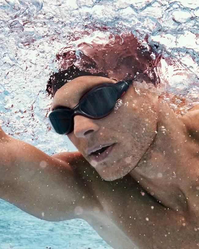 Mann schwimmt in Schwimmbecken, Schwimmbrille Speedo, Badekappe