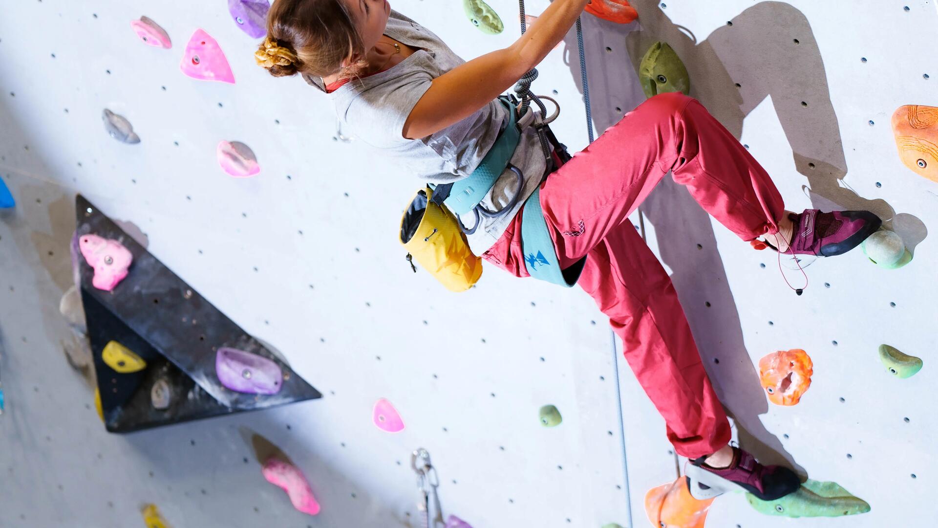 kobieta wspinająca się po ściance w uprzęży i butach do wspinaczki 