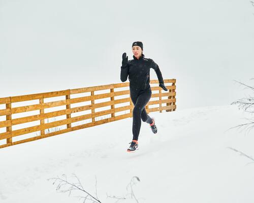 kobieta biegnąca po śniegu w odzieży do biegania z rękawiczkami na dłoniach 