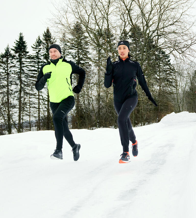 Um casal a correr protegidos do frio na neve