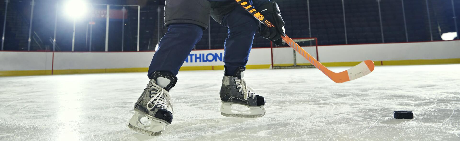 osoba w stroju do gry w hokeja stojąca na lodowisku trzymając kij hokejowy