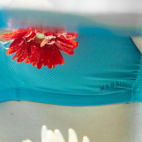 Close up a marca Nabaiji no fato de banho Lila em versão bikini, dentro de água e com uma flor à frente