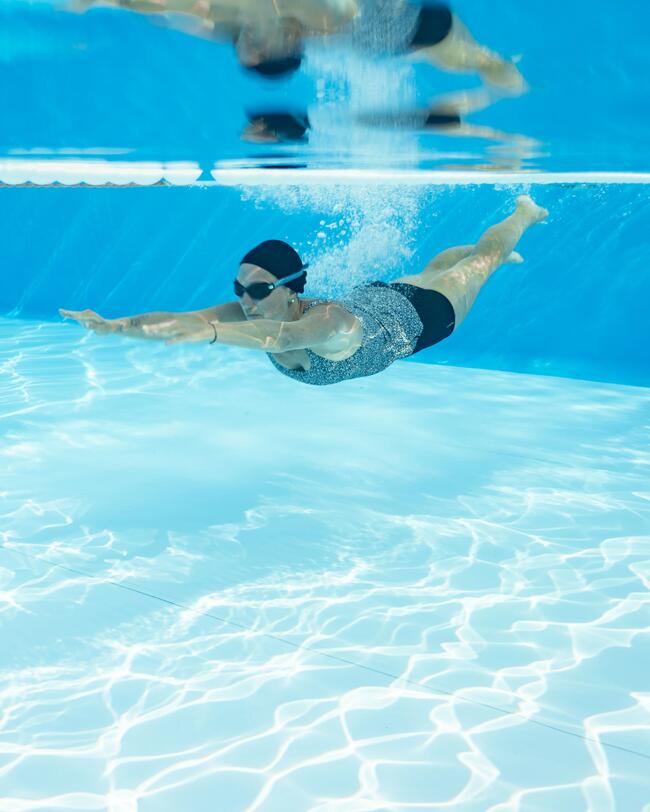 Frau taucht im Pool, Schwimmbrille, Badekappe, Tankini Schwimmbadeanzug