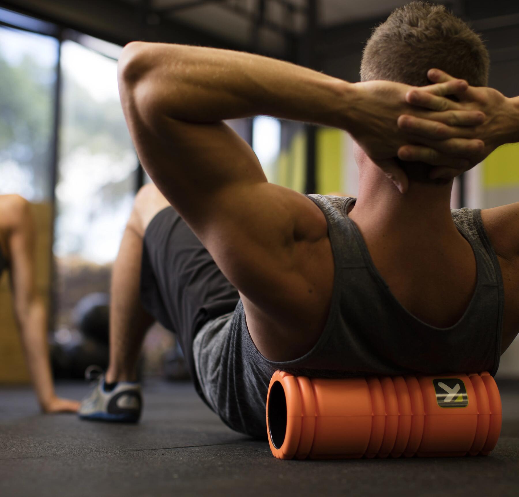 mężczyzna w odzieży fitness leżący na rollerze