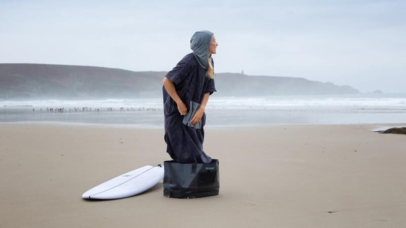 Surfista cambiándose con el poncho toalla