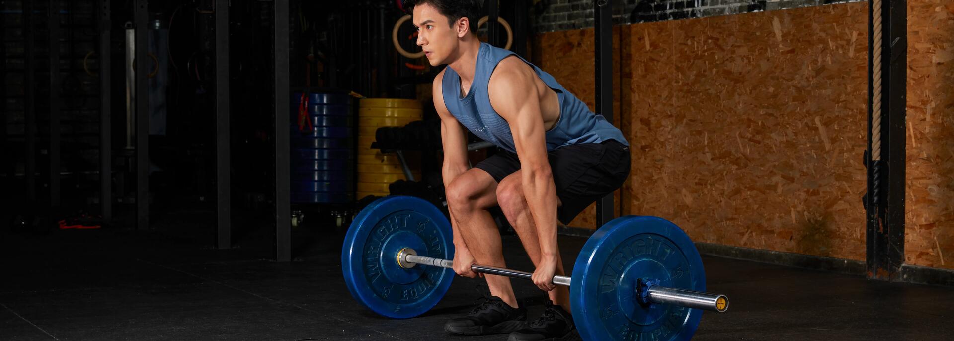 Mężczyzna w odzieży fitness wykonujący martwy ciąg ze sztangą