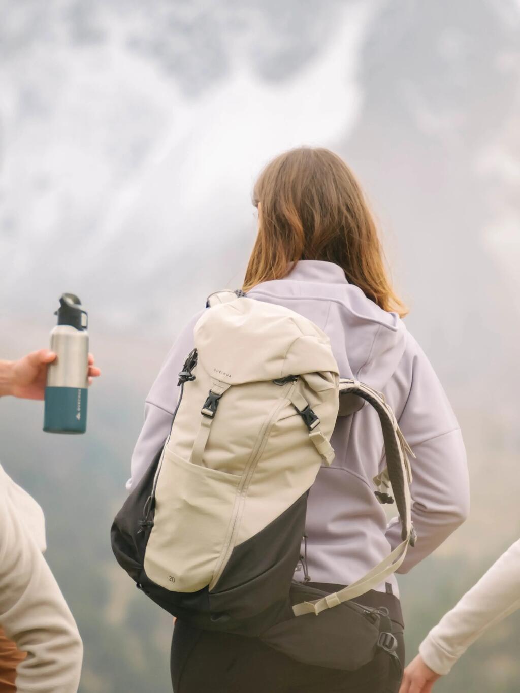 Ženska z belim in sivim nahrbtnikom v visokogorju.