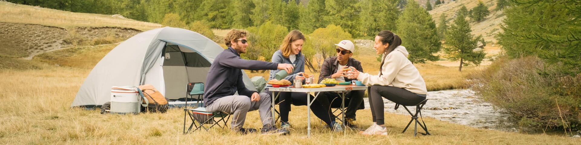 kobiety i mężczyźni jedzący posiłek na krzesłach turystycznych obok namiotu 