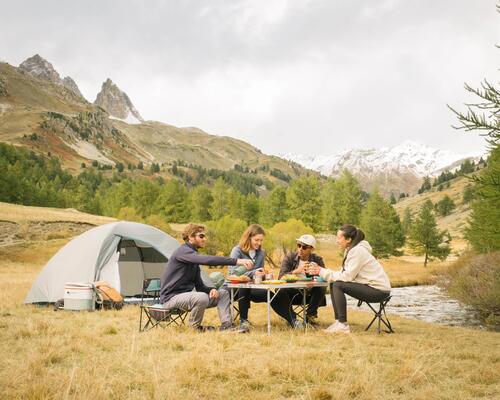 kobiety i mężczyźni jedzący posiłek na krzesłach turystycznych obok namiotu 