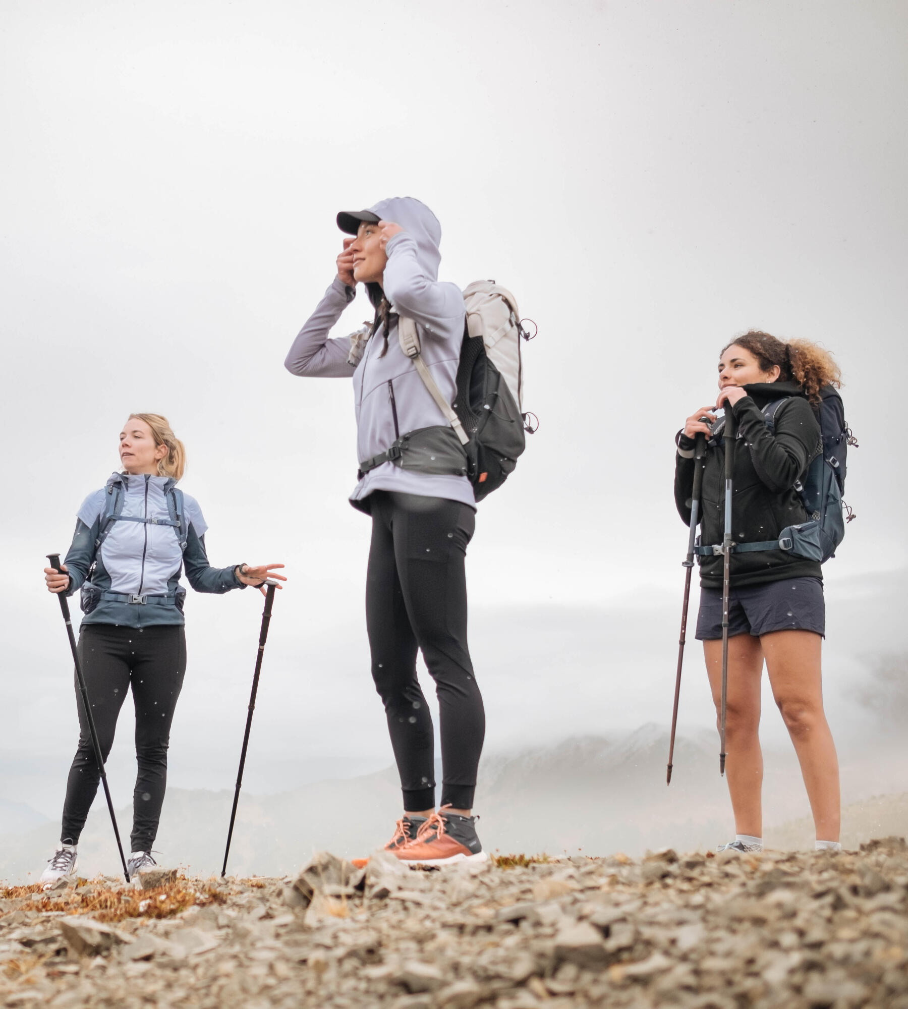 três raparigas a fazerem um caminada na montanha equipadas com mochilas e bastões