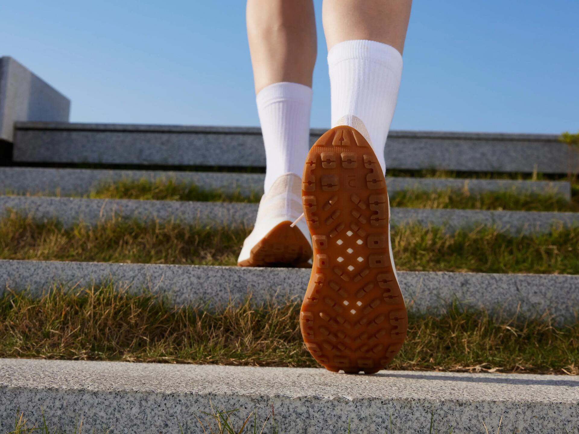 Osoba w obuwiu sportowym wchodząca po betonowych schodach