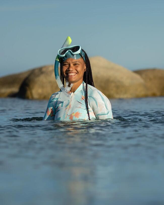 Frau steht im Wasser, Schnorchelmaske mit Schnorchel auf die Stirn geschoben, UV Shirt