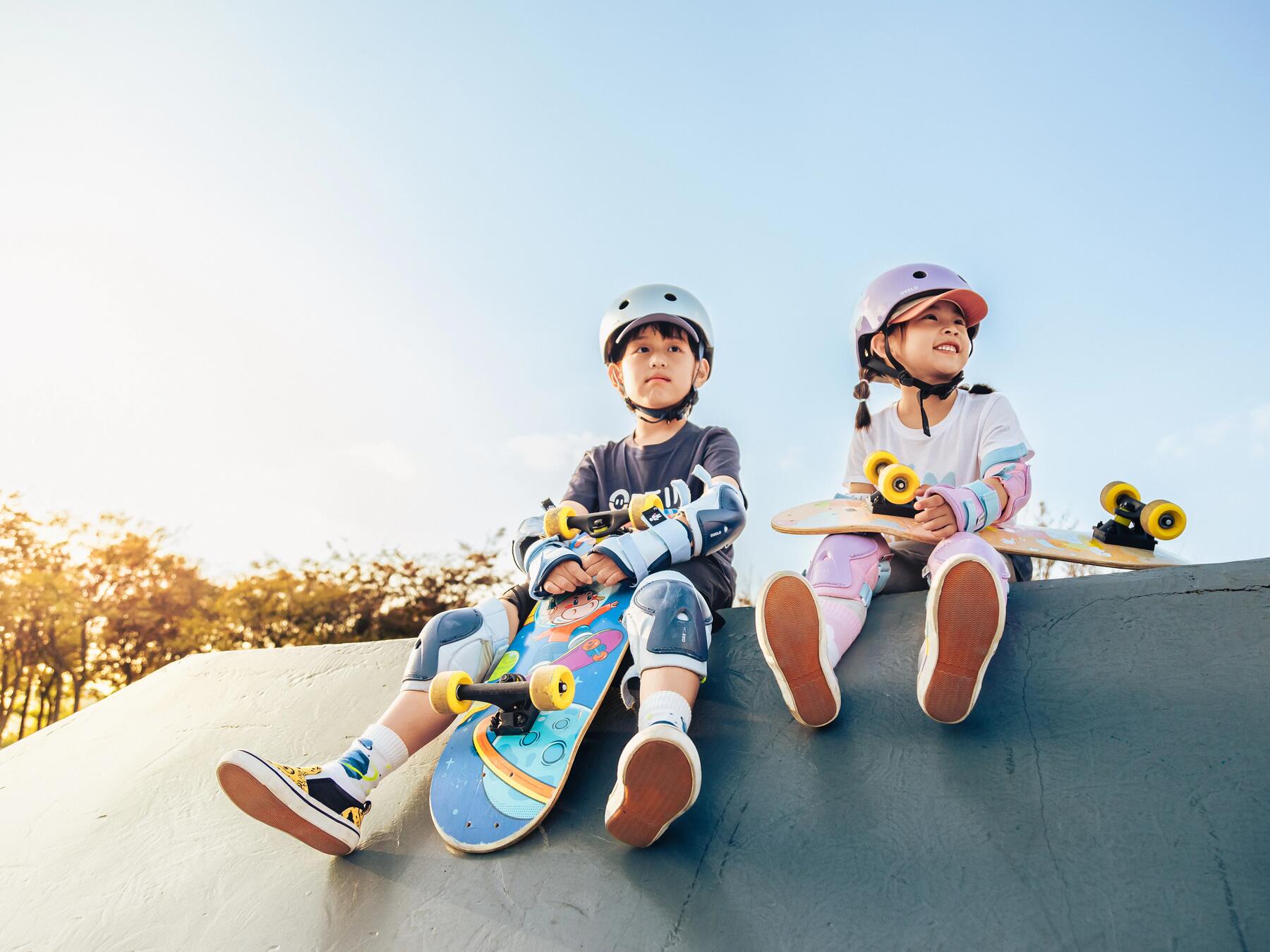 Dziecii z deskorolkami siedzące na skateparku