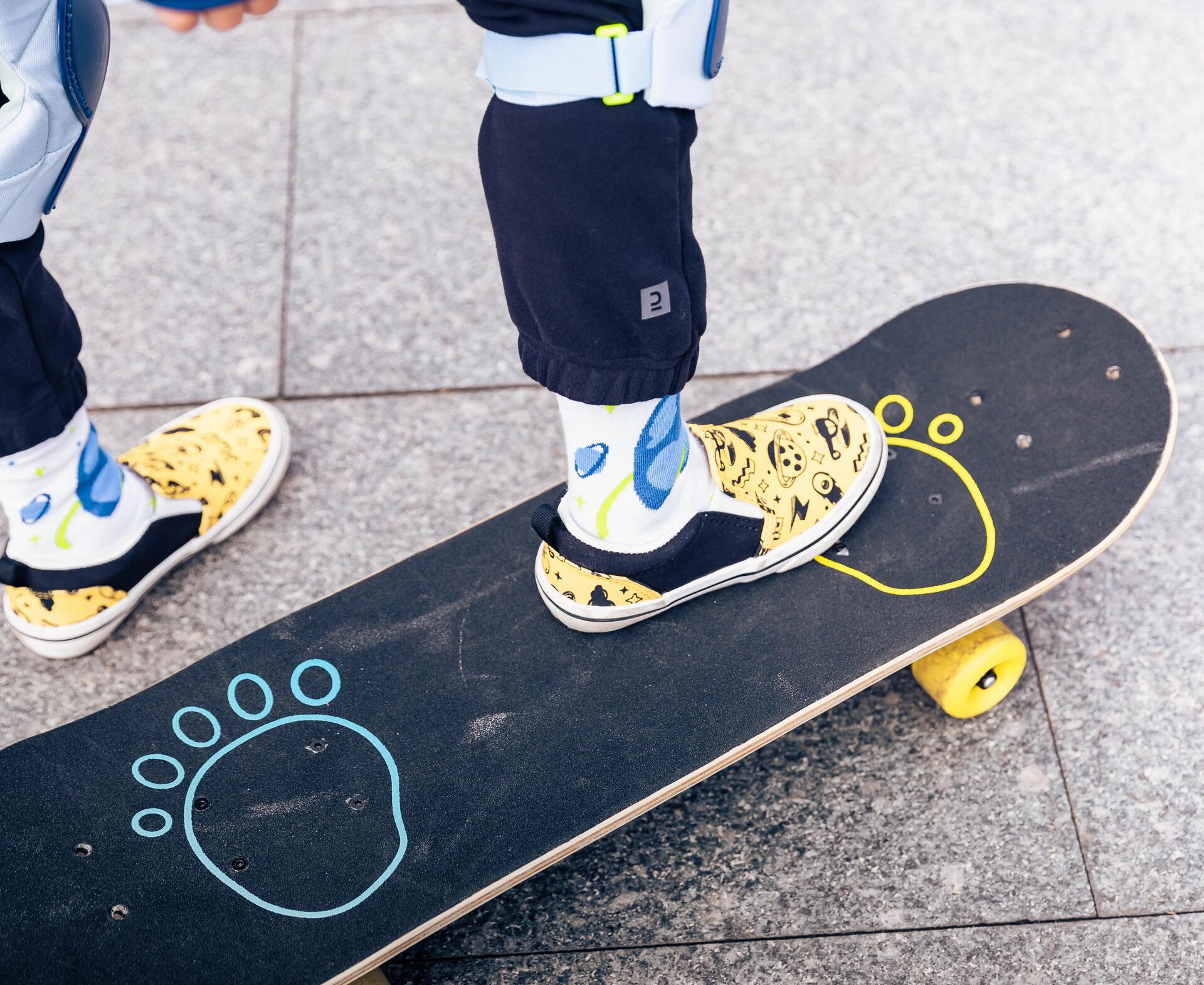A close of feet and skateboard with the right leg on the board and left leg on the ground
