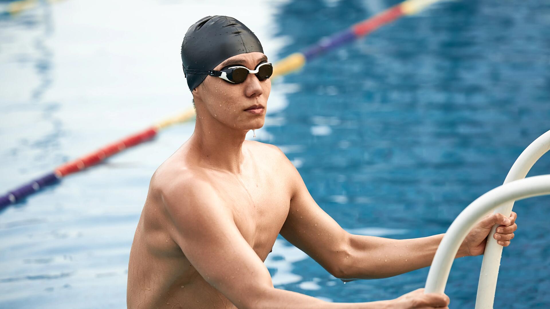 mężczyzna wychodzący z basenu w czepku i okularach do pływania