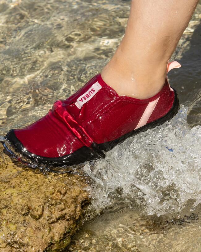 Vrouw staat op een steen onder water met Aquashoes aan