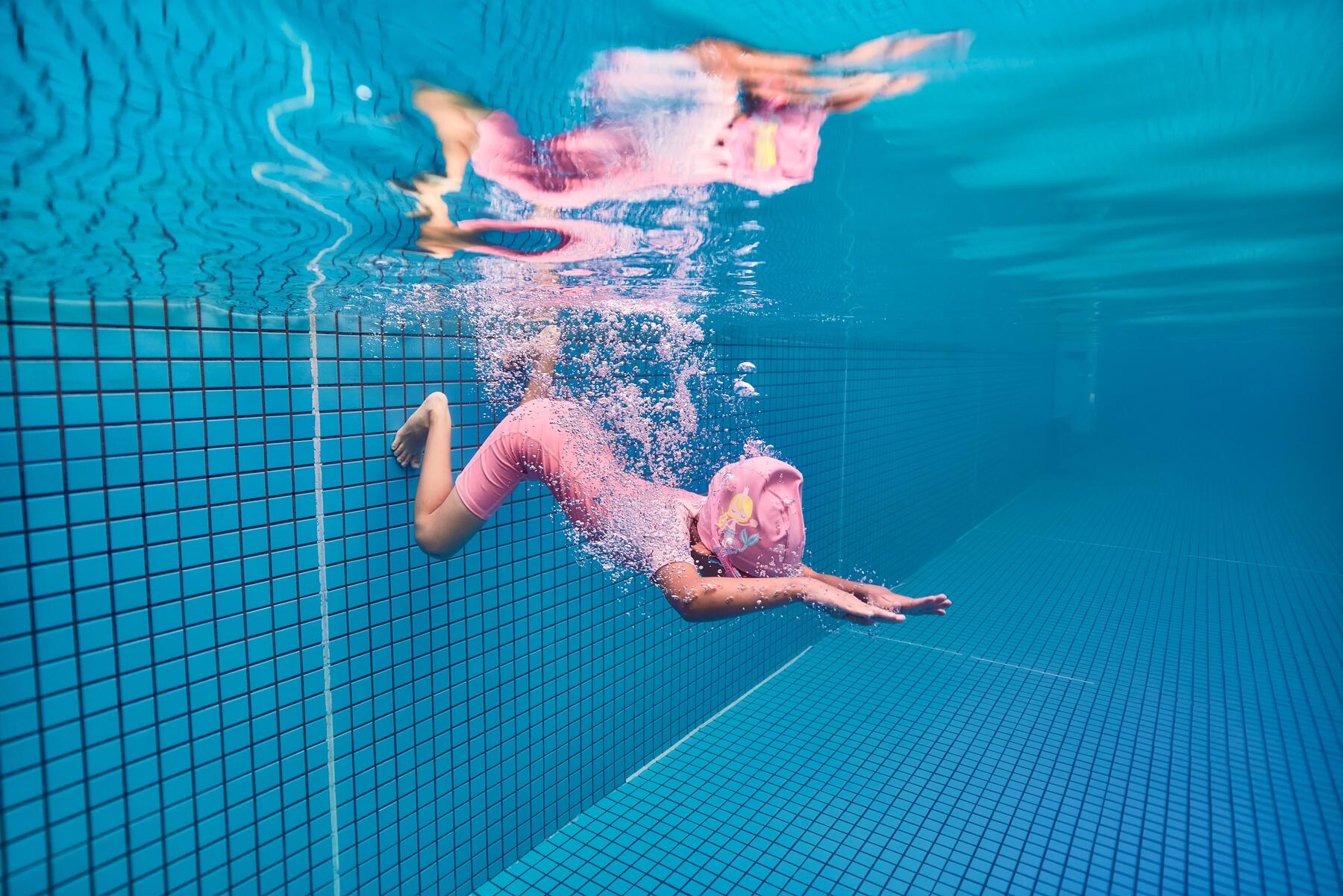 Dziewczynka robiąca ćwiczenia na basenie wspierające naukę pływania