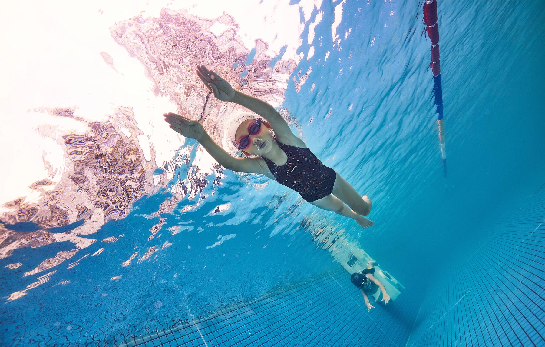 Dziecko w okularach pływackich płynące pod wodą