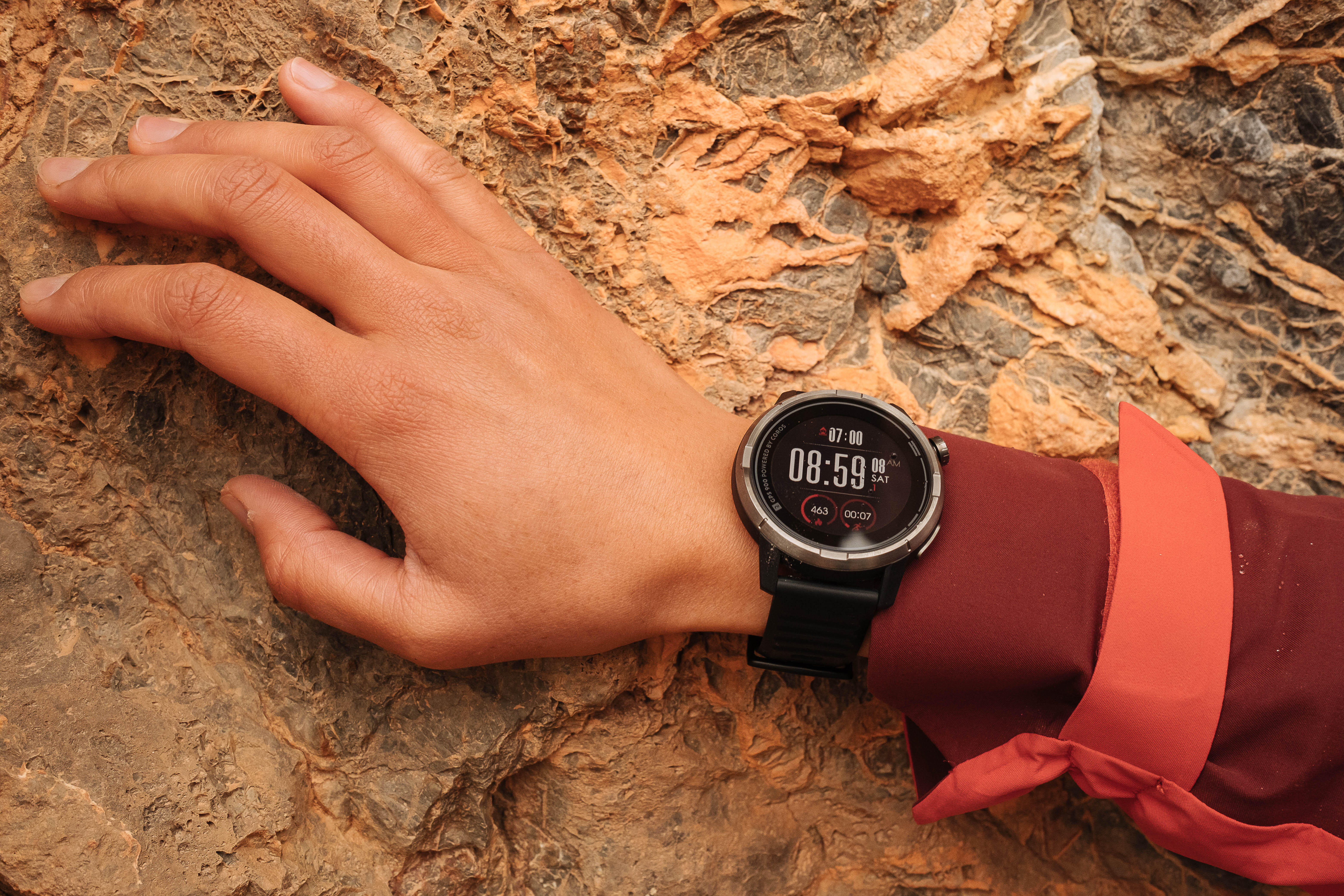 Person wearing a digital watch on rocky terrain