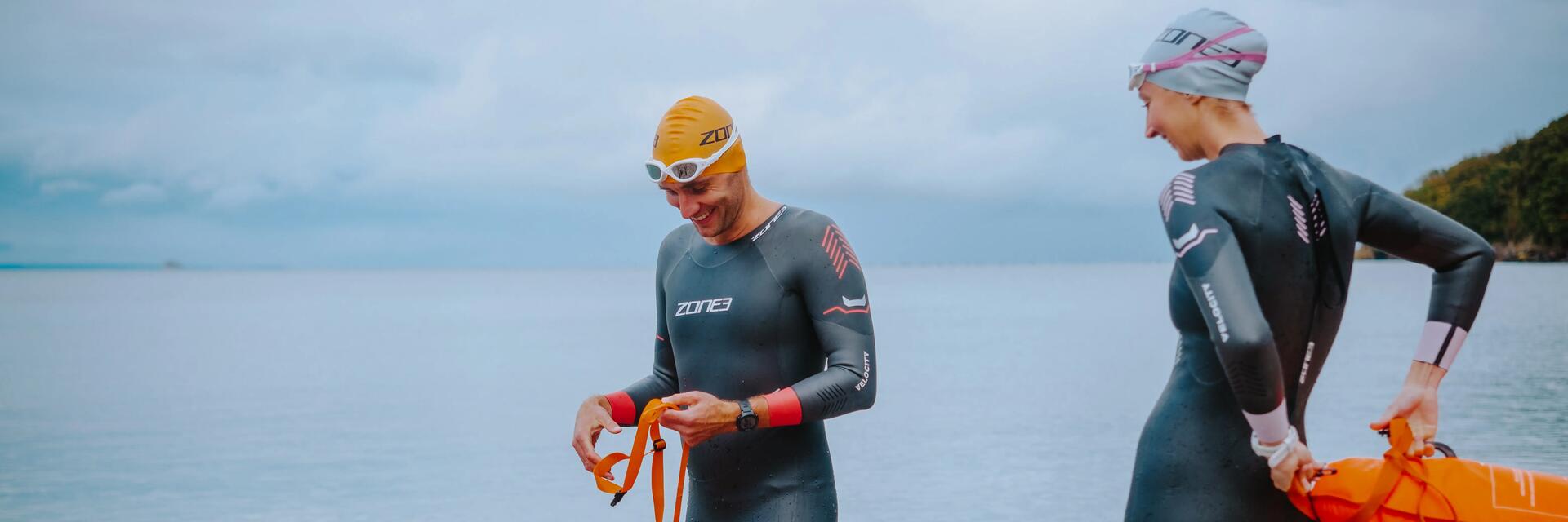 Kobieta i mężczyzna w czepkach piankach pływackich przygotowujący się do treningu pływackiego open water